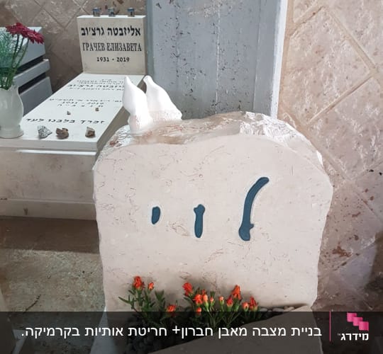 מצבות עם כיתוב בעברית ופרחים כתומים